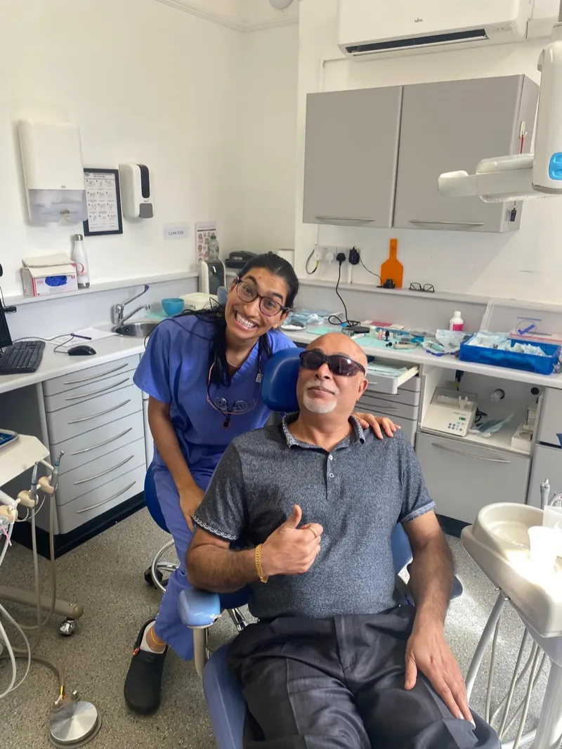 A patient giving a thumbs up from the chair, Dr Deesha beside him